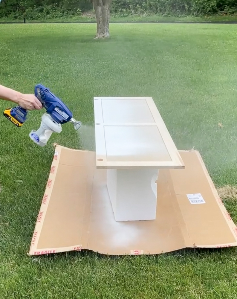 person using best sprayer for painting cabinets outdoors