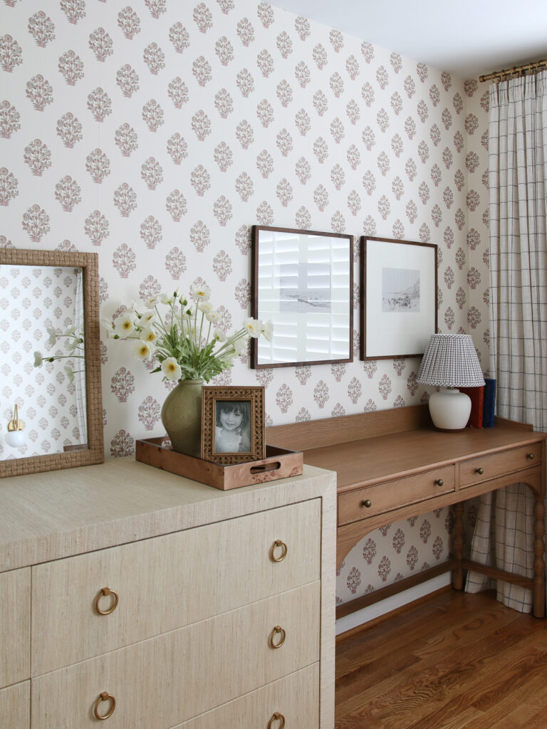 Block print wallpaper, grasscloth wrapped dresser, medium tone wood desk with mini lamp, windowpane drapes