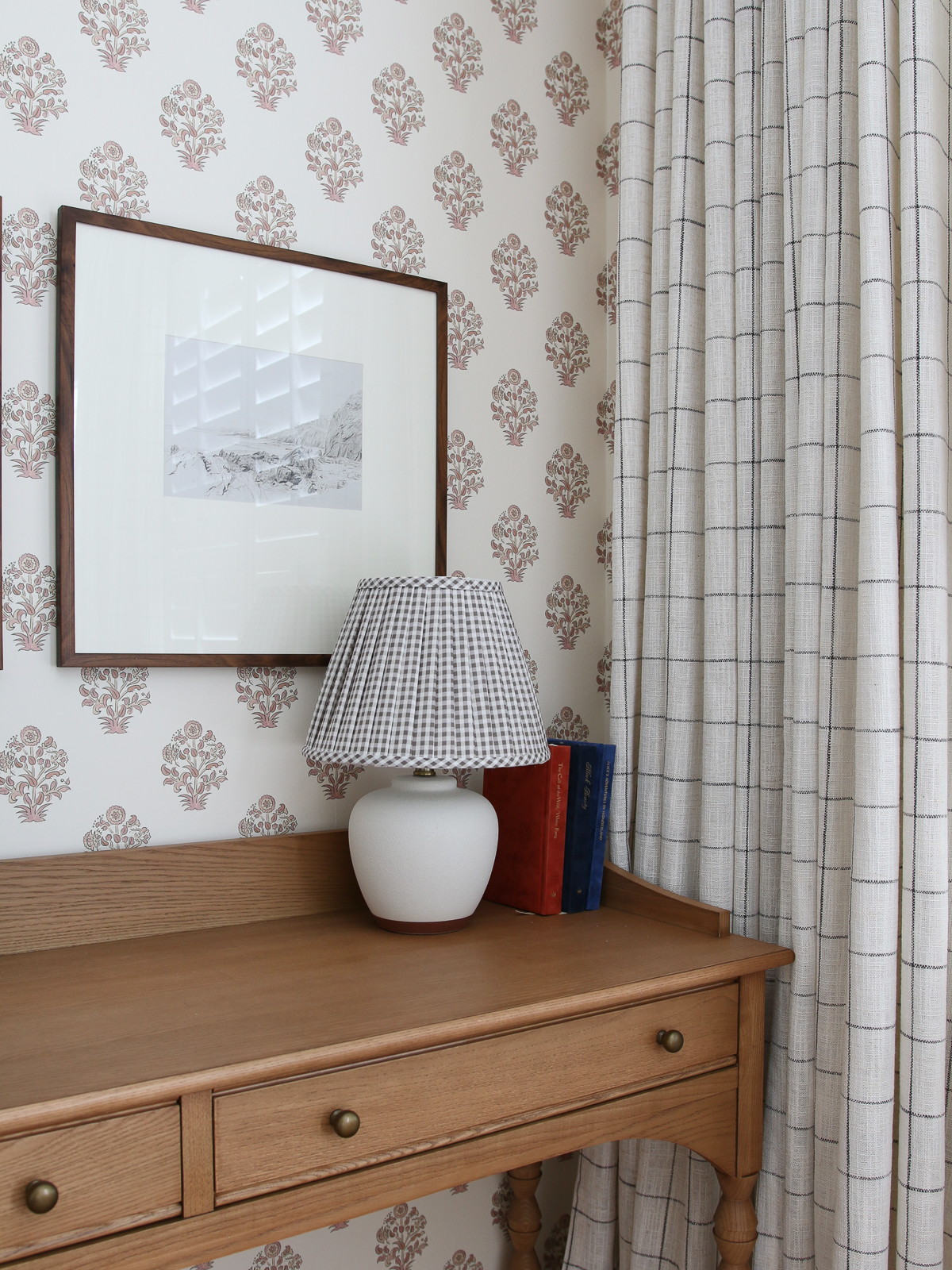 desk in corner with mini lamp with gingham pleated fabric shade, windowpane print window panels, framed art
