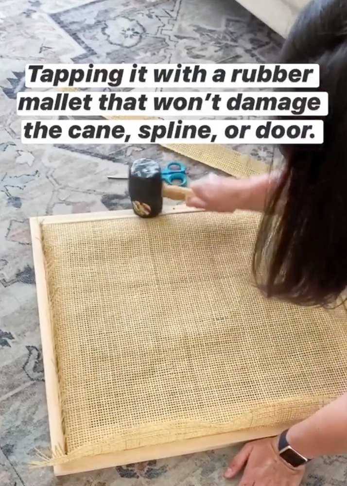 person demonstrating furniture and chair caning steps, using a rubber mallet to tap reed spline into groove