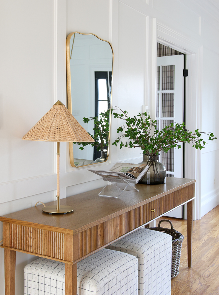 rattan table lamp styled on entryway console table with coffee table book and faux stems in a vase