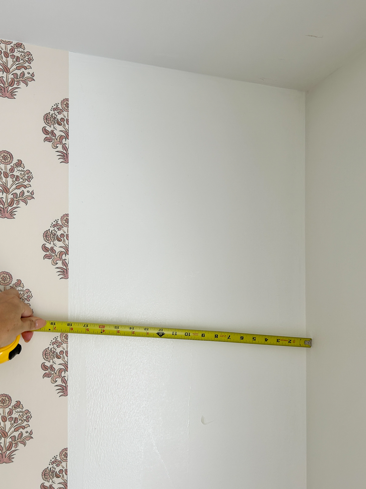 tape measure of distance from wallpaper to corner