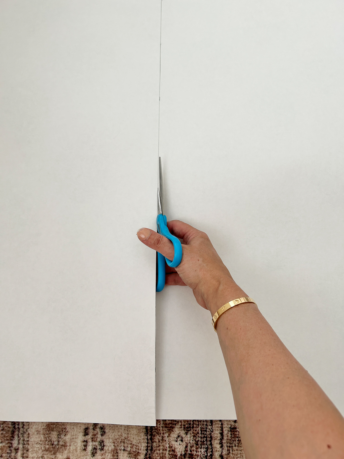 cutting a strip of wallpaper with scissors