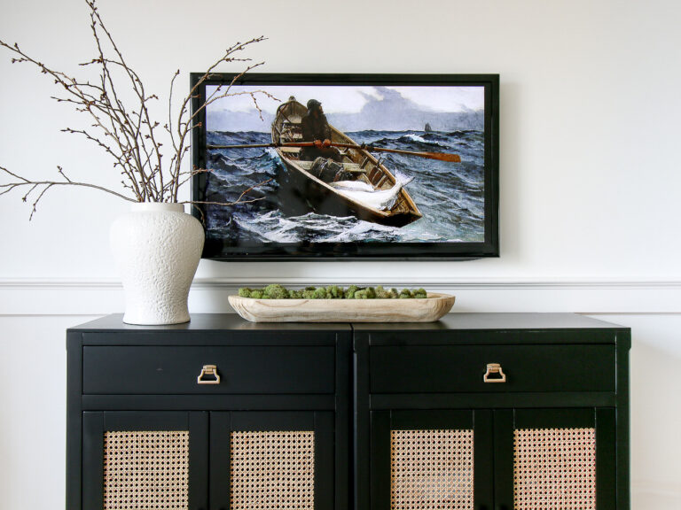 Tv mounted on wall above a console table, styled with white case and dough bowl, hidden cables in wall