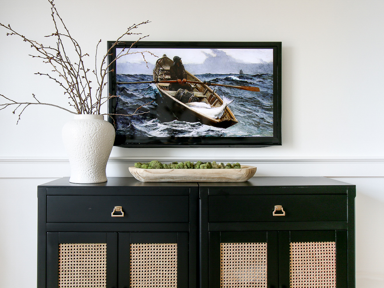 Tv mounted on wall above a console table, styled with white case and dough bowll