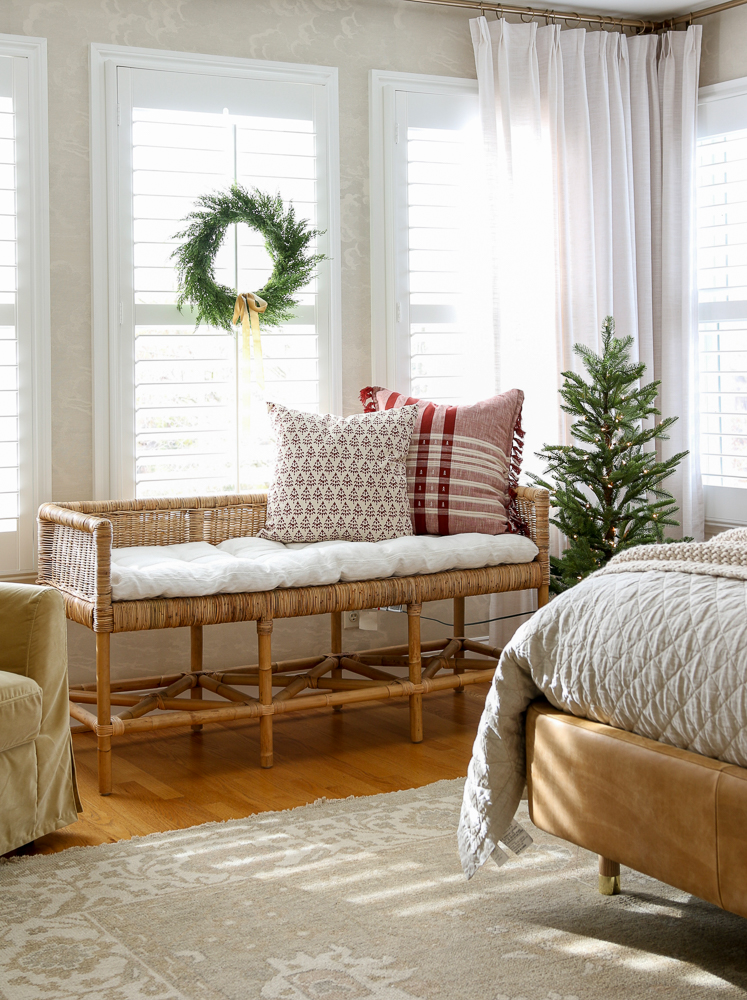 bedroom with holiday decor including block print throw pillows on Serena & Lily Shore bench, hand knotted area rug, linen drapes, interior window shutters