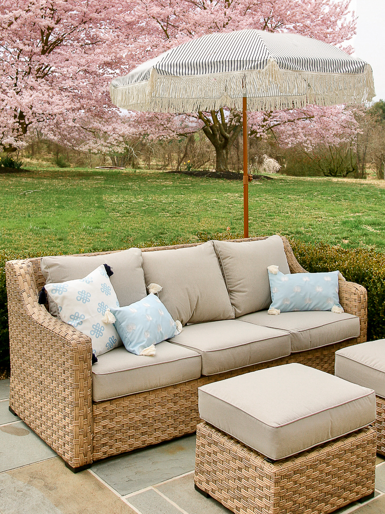 Walmart River Oaks patio furniture styled with throw pillows and outdoor umbrella, bluest patio, cherry blossoms in background