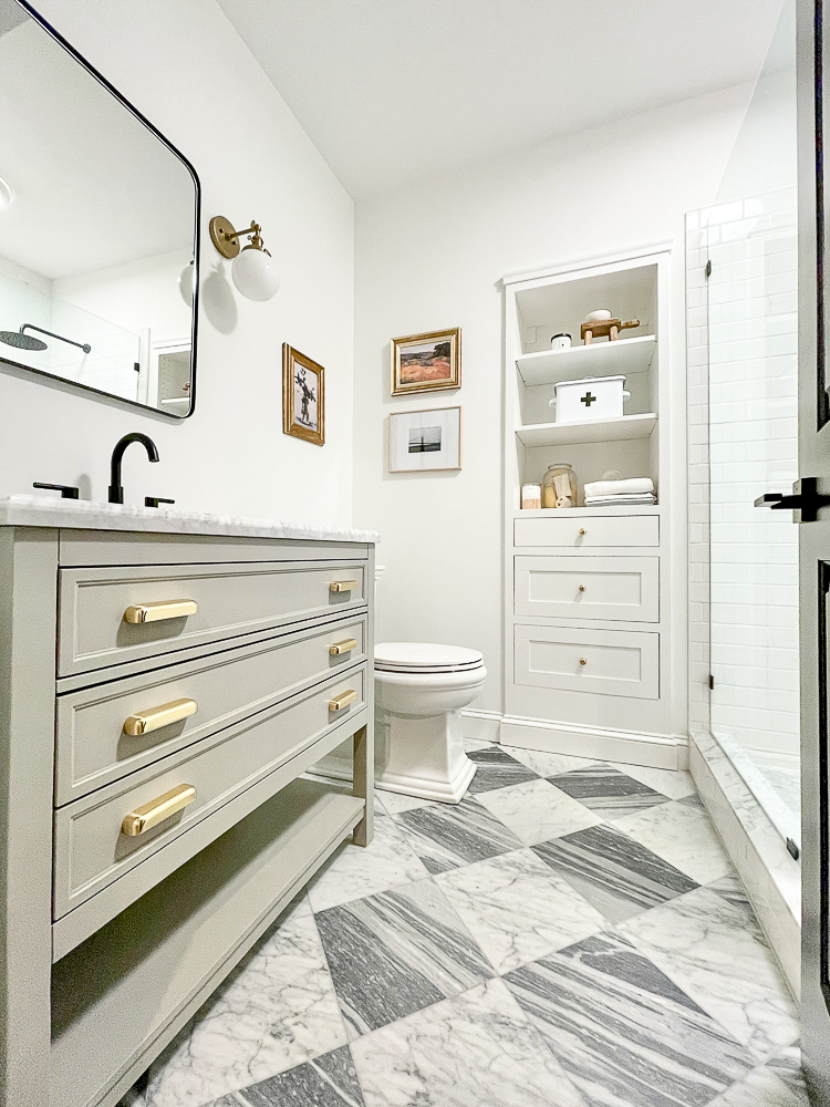 basement bathroom with white walls, gray and white marble checkerboard floors, brass hardware, mixed metal in bathroom