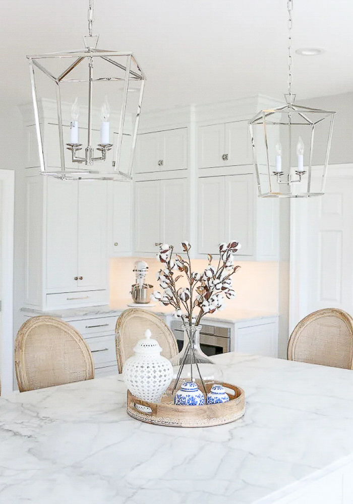white kitchen with polished nickel pendants and cabinet hardware, honed marble countertops