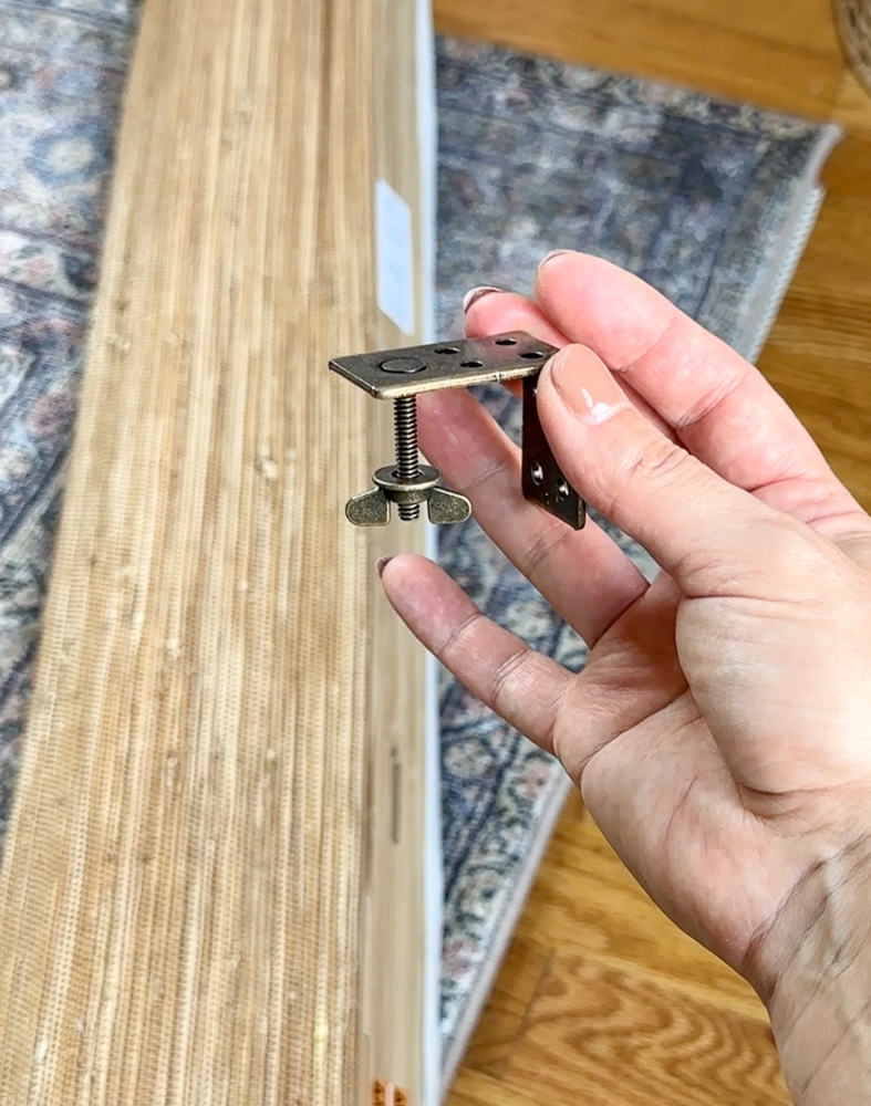 person holding hardware used to install woven shades 