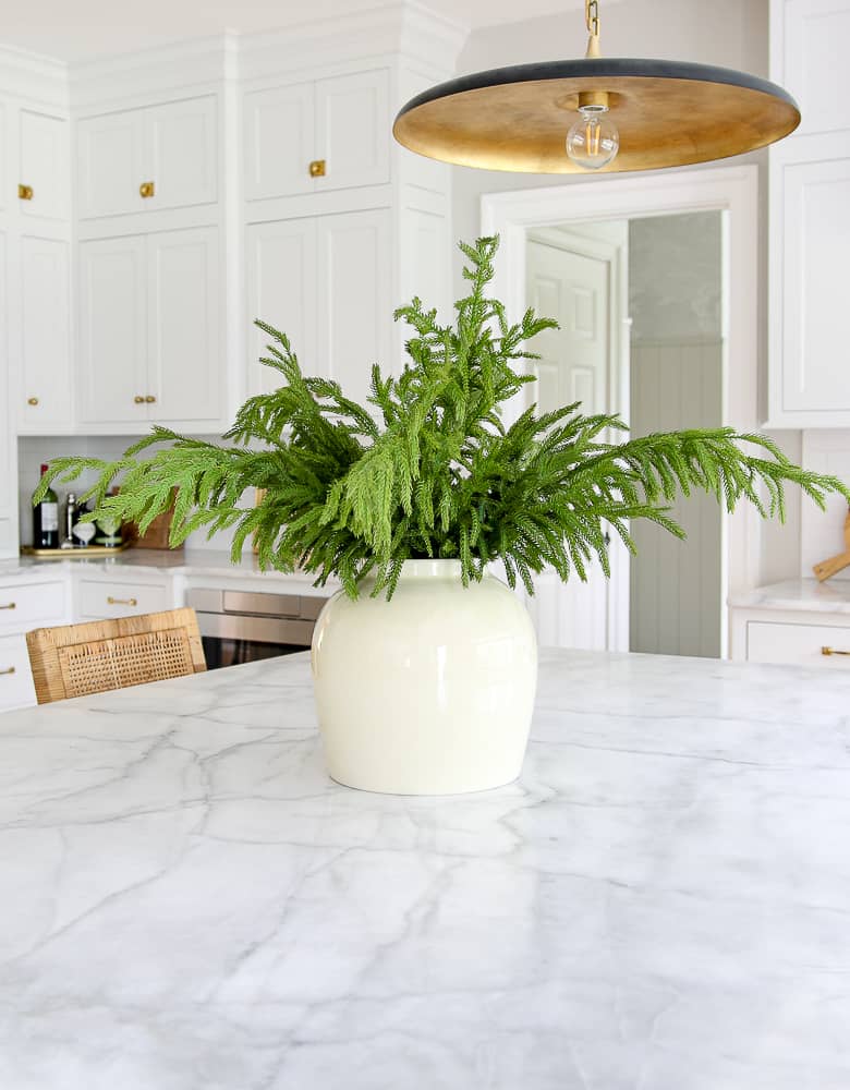 vase and norfolk pine stems on marble kitchens island countertop, Christmas decorating in the kitchen