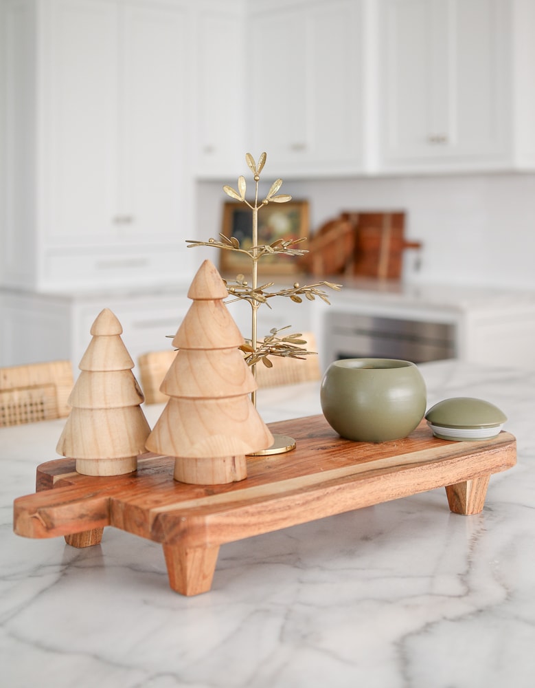 Christmas decor items styled on kitchen island, candle and trees