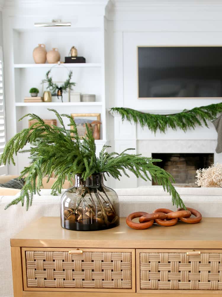 Norfolk pine branches styled in vase and matching fireplace garland in background