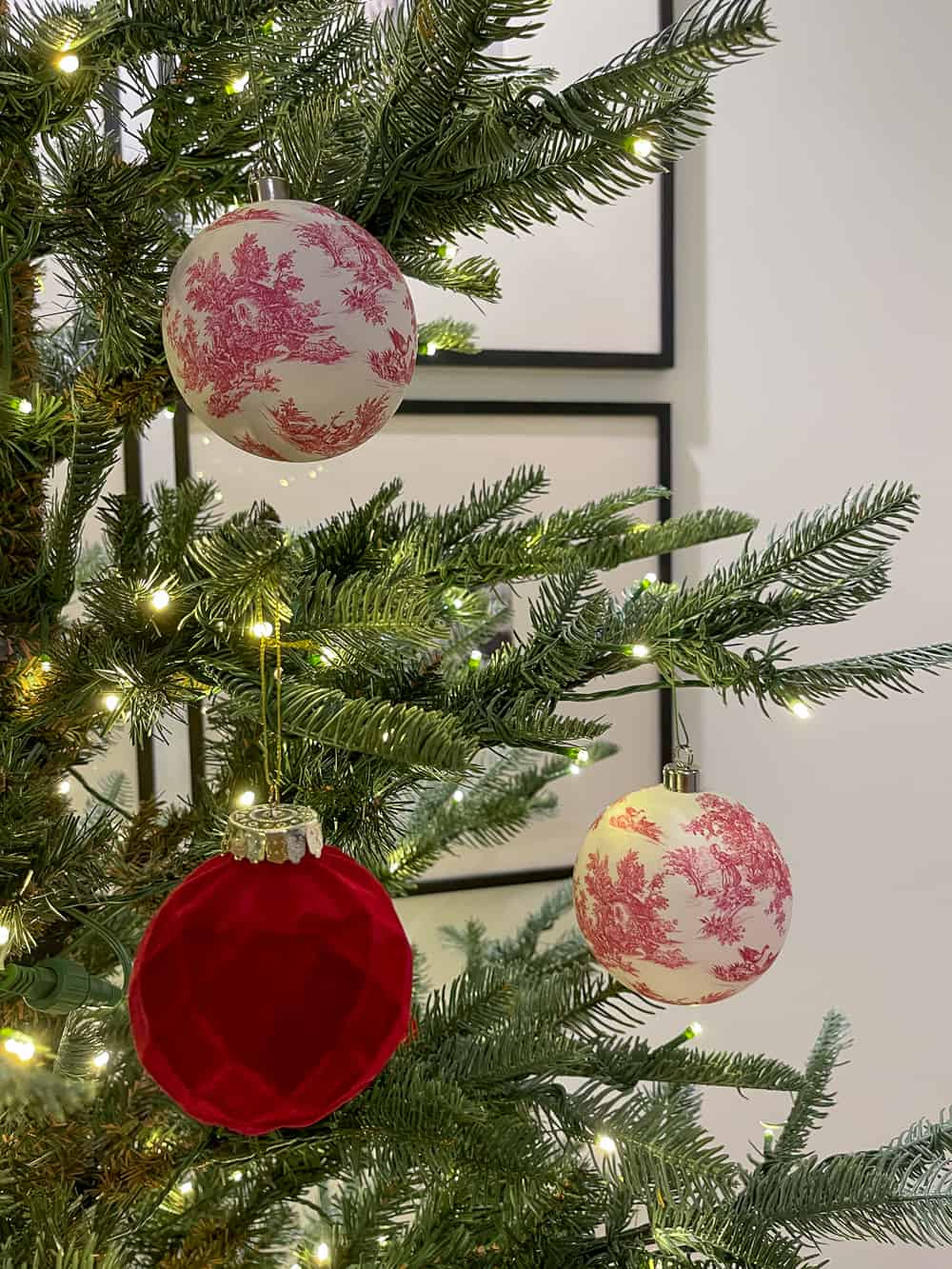 pre-lit artificialtree in arched niche with grid photo gallery in the back red and white toile  and red velvet ornaments