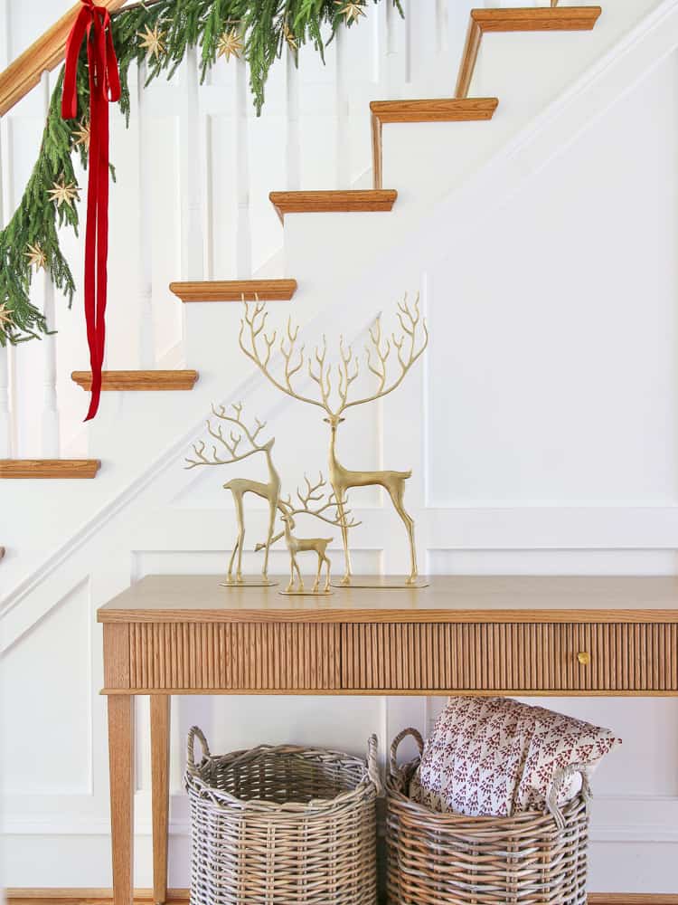 set of Pottery Barn brass reindeer on McGee and Co Pieter console table, baskets, garland and ribbon on stairway 