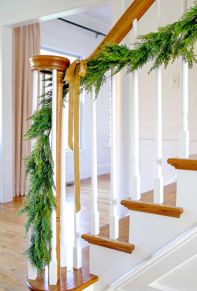 cedar garland draped on stairway with light brown ribbon, minimalist christmas decor