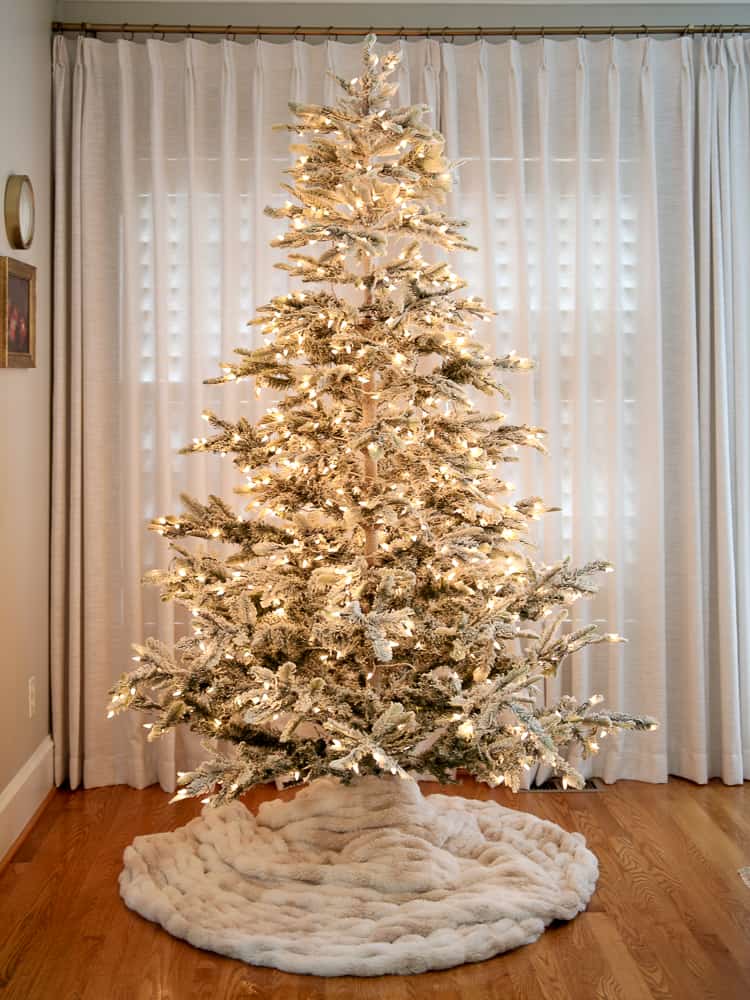 flocked aspen fir christmas tree with a fur blanket dIY tree skirt, lights are on