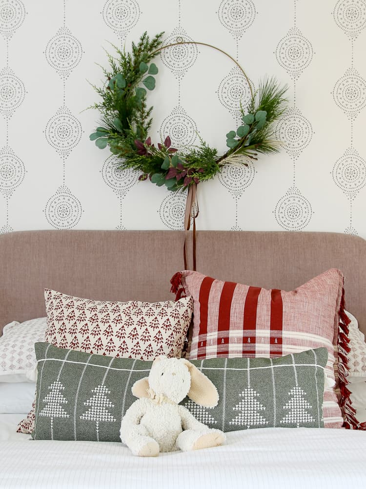 hang wreaths above a bed, Christmas wreath hanging on a wall above a bed in a girl's room, mauve velvet heardboard, block print holiday pillows, Serena and Lily wallpaper