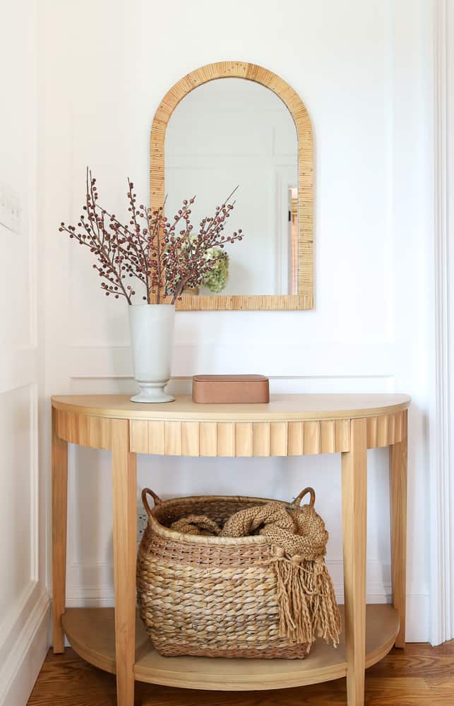 entry console table decorated with winter berry stems, basket with thro blanket, ideas for winter decorating after Christmas