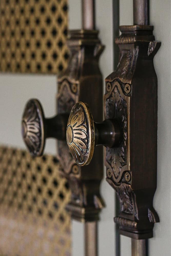 close up of antique brass Cremone bolts on home office cabinet doors