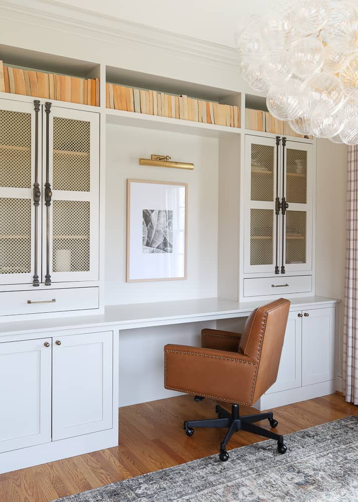 home refresh with paint, walls and builtin cabinets painted SW Accessible beige, leather desk chair, bubble chandelier, hardwood floors with loloi cloud pile rug