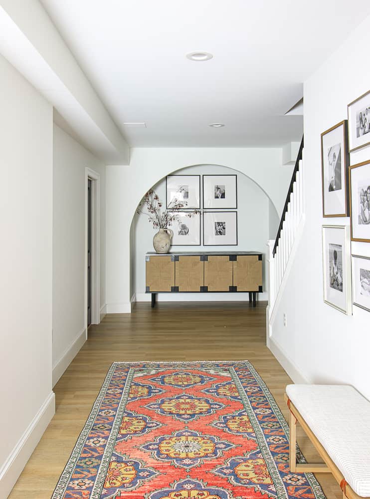 same basement view with decor added, cabinet in arched niche, photo gallery wall, LVP floors