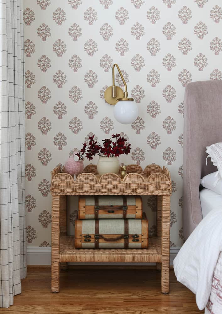 nightstand without a lamp, sconce on the wall above the bedside table, scalloped rattan side table, block print wallpaper