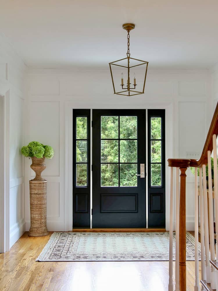 entryway with black front door and white walls, red oak traditions hardwood floors exposed to sunlight coming through windows